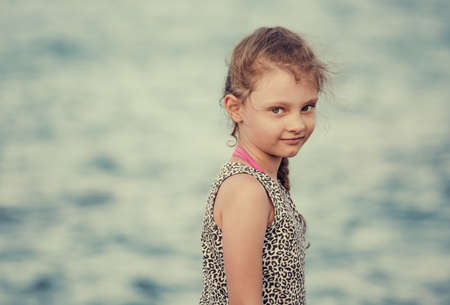 Happy kid girl relaxing and joying on blue sea background and vacation sky. Closeup holidays...
