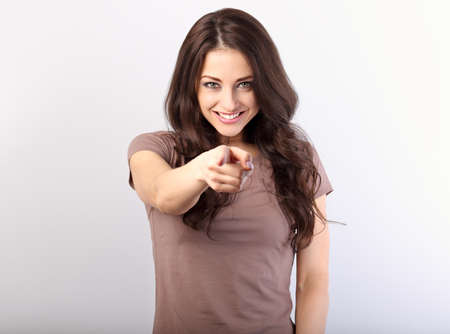 You made your choice and got it! Playful attractive business woman pointing of you the finger showing hand on the camera. Casual closes on brunette model on blue background. Happy toothy smile. Closeup portraitの写真素材