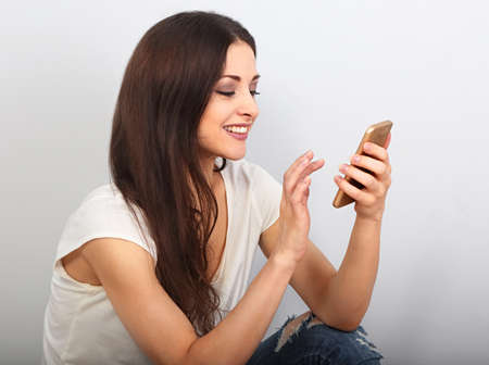 Happy smiling young positive woman texting on mobile phone and looking positive. Closeup portraitの写真素材