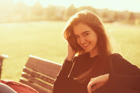Beautiful smiling young woman looking happy with long amazing hair on nature bright sunset summer background. Closeup portraitの写真素材