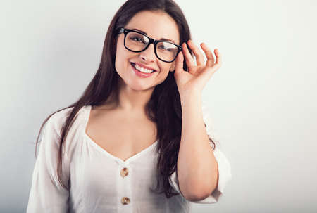 Beautiful natural smiling woman in modern glasses looking happy on blue background. Closeup portrait