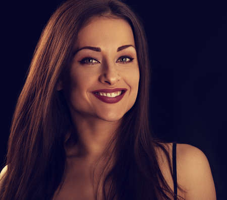 Beautiful makeup woman with long hair looking happy on black background. Closeup portrait of natural happiness. Toned colorの写真素材