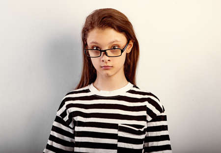 Surprising funny kid girl with long hair style in fashion eyeglasses in t-shirt making control excited physiognomy with big eyes and looking Closeup toned vintage portraitの写真素材