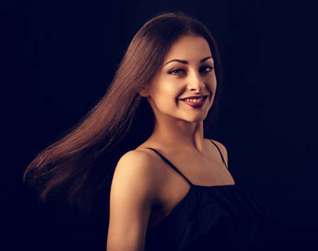 Beautiful makeup woman with long hair in action looking happy on black background. Closeup portrait of natural happiness. Toned vintage colorの写真素材