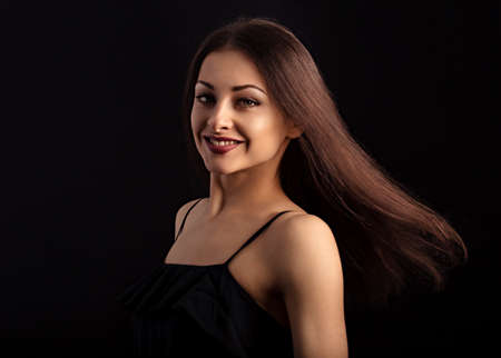 Beautiful makeup woman with long hair in action looking happy on black background. Closeup portrait of natural happiness. Toned colorの写真素材