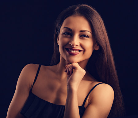 Beautiful makeup smiling woman with long hair in action looking happy on black background. Closeup portrait of natural happiness. Toned colorの写真素材