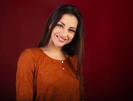 Beautiful happy smiling woman on dark red background with empty copy space. Closeup front view portrait of natural female. Valentine's day emotionの写真素材