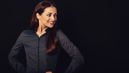 Beautiful thinking excited smiling business woman with folded arms on presentation on black background with empty copy space for text. Closeup toned vintage portraitの写真素材