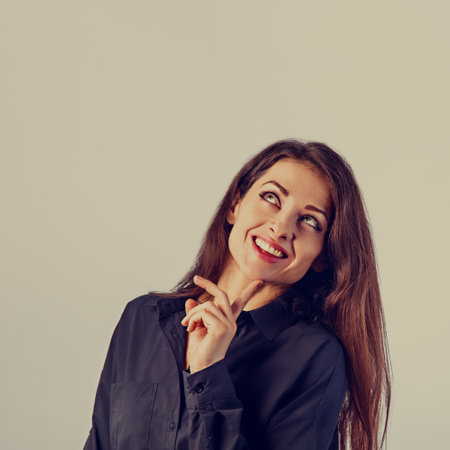 Beautiful confident calm thinking smiling business woman standing and looking in black cotton style shirt on blue light background with empty copy space for text. Closeup toned color portraitの写真素材