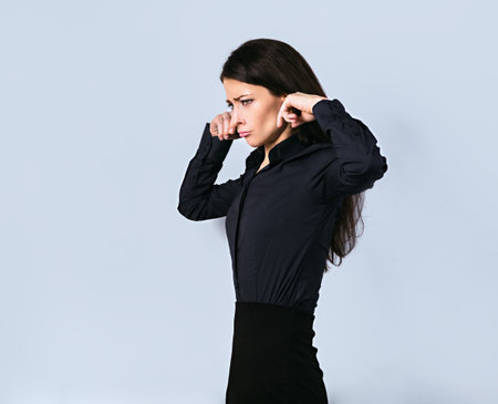 Beautiful business tired woman covering the ears the fingers to not want listening to anything sounds on blue background. Closeup portraitの写真素材
