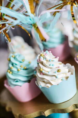 Cupcakes with white cream and colored balls on a gold standの写真素材