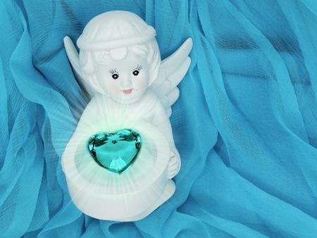 gem crystal heart in angel's hands on silky cloth love conceptの写真素材