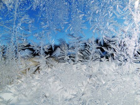 snowflakes ice pattern with sunlight on winter window glassの写真素材