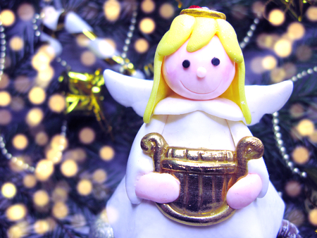 happy angel on branch of tree christmas background with garland lightsの写真素材