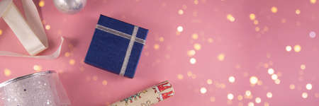 Christmas concept. Banner. Gift boxes, paper's rools, white and silver ribbon and silver ball on pink backgruond. Preparation for holidays. Top view and copy space.の写真素材