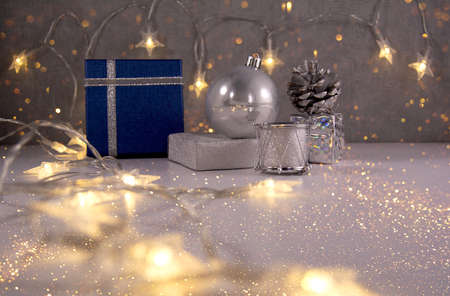 Christmas composition. Blue christmas gifts, silver decoration ball, ribbon, cone, drum and golden sparkles. Front view stile.の写真素材