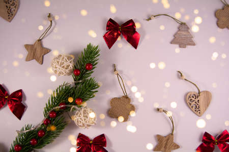 Christmas composition. Red bows, wooden toys, garland and decorative branch on a white background with golden lights. Holiday concept. Top view.の写真素材