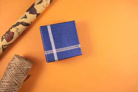 Preparation for holidays. Blue gift boxes, papers rools and rope on orange backgruond. Preparation for holidays. Top view and copy space.の写真素材