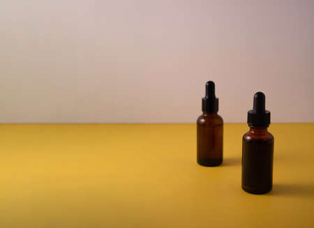 Beauty product concept. Bottle of serum on yellow and white backgrounds. Front view, copy spaceの写真素材