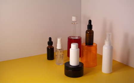 Beauty product concept. Cosmetic containers on the orange and red transparent podium. Front view, copy spaceの写真素材