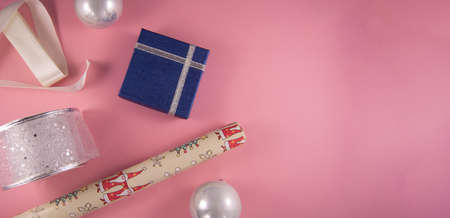 Christmas concept. Gift boxes, papers rools, white and silver ribbon and silver ball on pink backgruond. Preparation for holidays. Top view and copy space.の写真素材