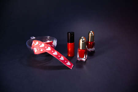 Valentines Day Background. Red lipstick and nail polish on a black background.の写真素材