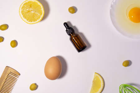 Cosmetic product. Natural ingredients for the preparation of the hair mask: lemon, eggs, olive oil. Olives, hairbrush and whisk for stirring. Hair and skin care maskの写真素材