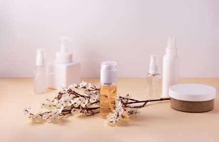 Beauty product concept. Cosmetic containers and skin care products on light background and a branch of small white flowersの写真素材