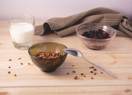 Healthy food. Healthy breakfast. A bowl with muesli, a bowl with frozen cherries and blackberries, a glass of milk and a kitchen napkin on a wooden background.の写真素材