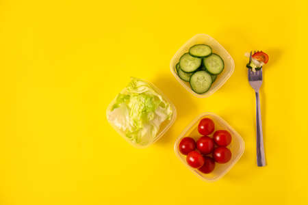 Containers with fresh vegetables on a yellow backgroundの写真素材