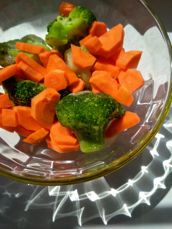 Carrots and broccoli in a plate. Sunlight falls on fresh vegetablesの写真素材