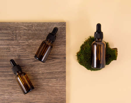 Serum bottles on ceramic tiles with wood texture and pattern on a beige background. A bottle of...