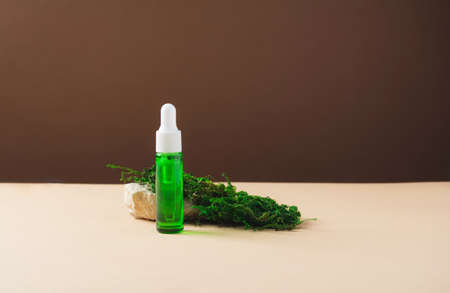 Serum and oil cosmetic bottle with concrete stone and moss on brown and beige background. Liquid...