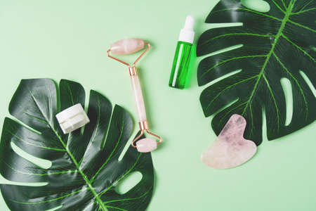 Roller and gua sha massage scraper and cometic product on a green backgroundの写真素材