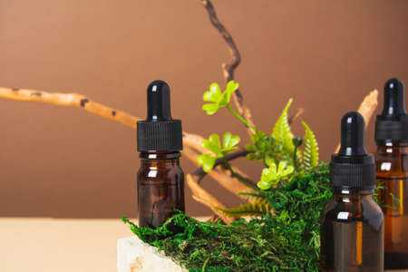 Set of bottles with serum or oil with natural materials on brown and beige backgroundの写真素材