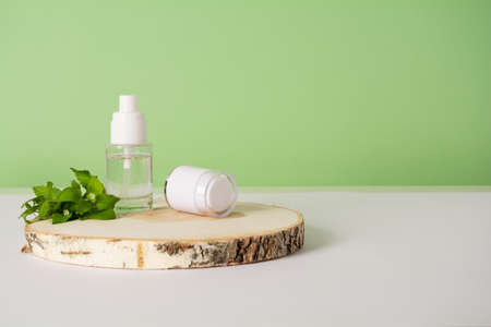 Cosmetics bottle with beauty product and wild plants on green background. Liquid skin or hair care product. Natural organic cosmetic, healthy beauty conceptの写真素材