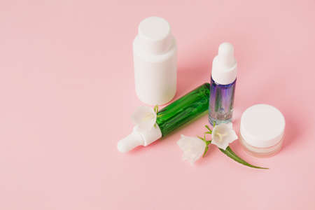 Cosmetics bottle with beauty product and wild plants on pink background. Natural skin and hair care. Wellbeing concept. Copy spaceの写真素材