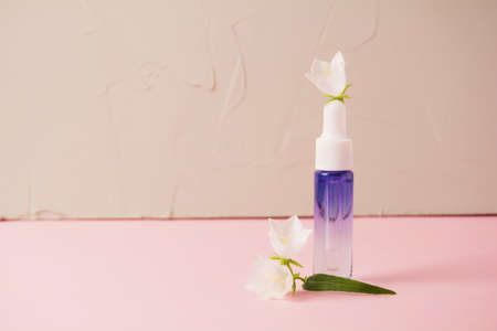 Serum glass bottle on a pink background. Liquid skin or hair care product. Natural cosmetics...