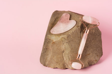 Roller and gua sha massage scraper on natural stoneの写真素材