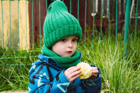 Child eating delicious apple outdoors, fruit snack. Healthy food concept. Vitamins in food