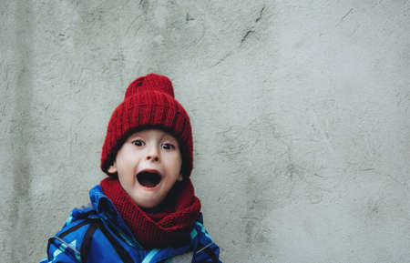 Portrait of a screaming child with a pumpkin. The kid expresses fear. Halloween and holiday concept. Copy spaceの写真素材