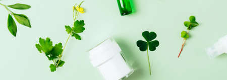 Banner. Cosmetics bottle with beauty product and wild plants on green background. Liquid skin or...