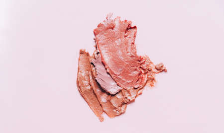 Close-up smear of multicolored lipstick with shimmery particles on a pink background. Texture backgroundの写真素材