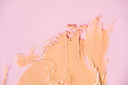 Beige foundation smear in blur on a pink background. Beautiful textured background for your ideasの写真素材