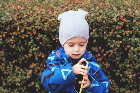 Portrait of a child with a phone in his hands, who looks at the telephone. Childhood communication, technology and communication concept. Copy spaceの写真素材