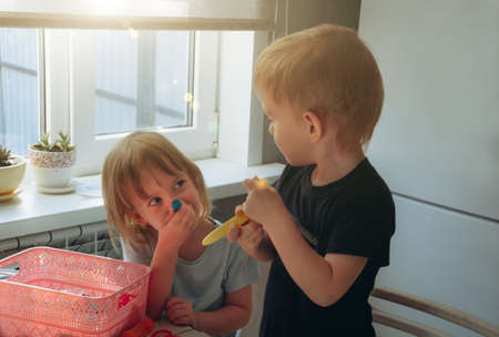 Children playing play dough. The girl leaned plasticine against her nose. Child development concept, fine motor skills development.の写真素材
