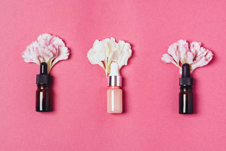 Serum in glass bottles with carnation petals on a pink background. Aromatherapy oil, natural cosmetics concept. Minimalism.の写真素材