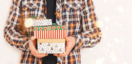 A man in a shirt holds various gift boxes. Christmas and holiday concept. Copy spaceの写真素材