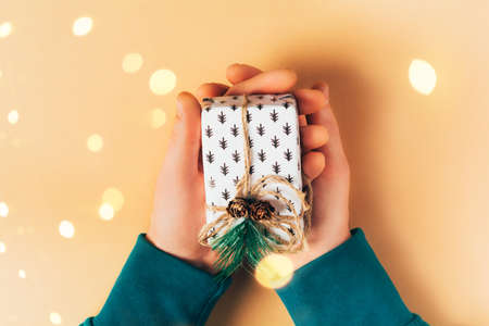 Male hands holding gift box on beige background. Eco-friendly concept, zero waste christmasの写真素材