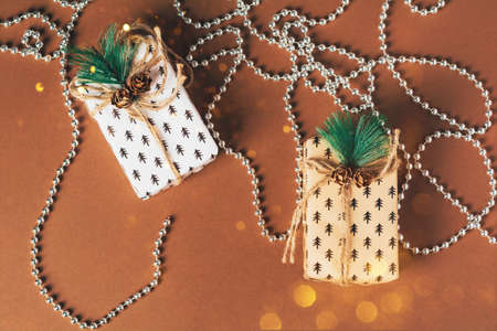 Christmas gift box with silver beads and sparkles. Preparation on the eve of the holidays of Christmas and New Year on a brown background. Eco-friendly concept, zero waste christmas.の写真素材